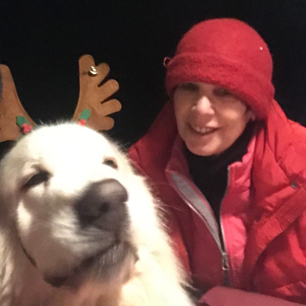 glückliche Kundin mit roter Alpakamütze auf dem Kopf neben ihrem Hund, der ein Geweih trägt